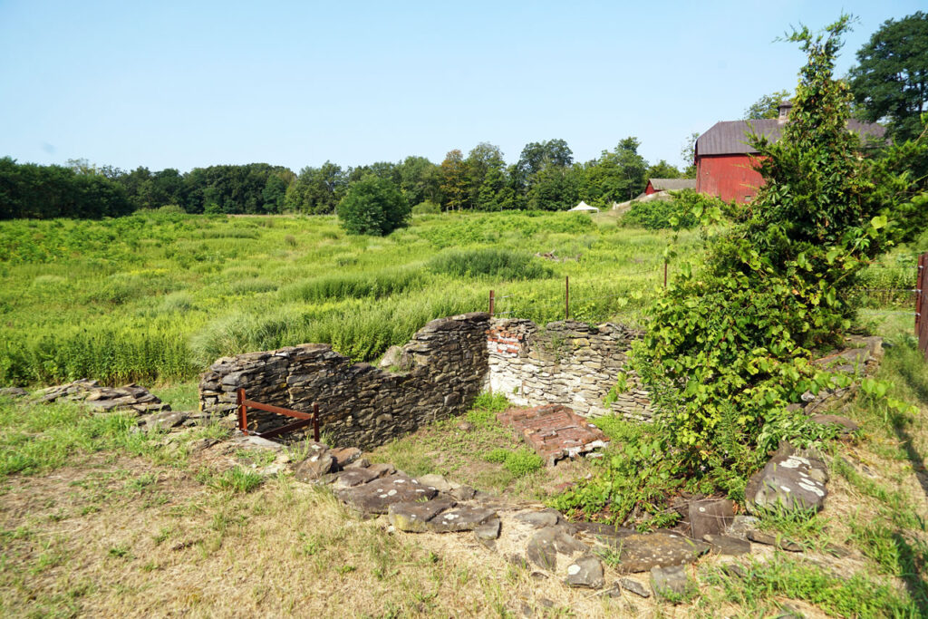 The Brezie Farmhouse foundation. The collapsed chimney is in the center; an Olana barn is in the background. Photo by Annik LaFarge, author of Composing Olana