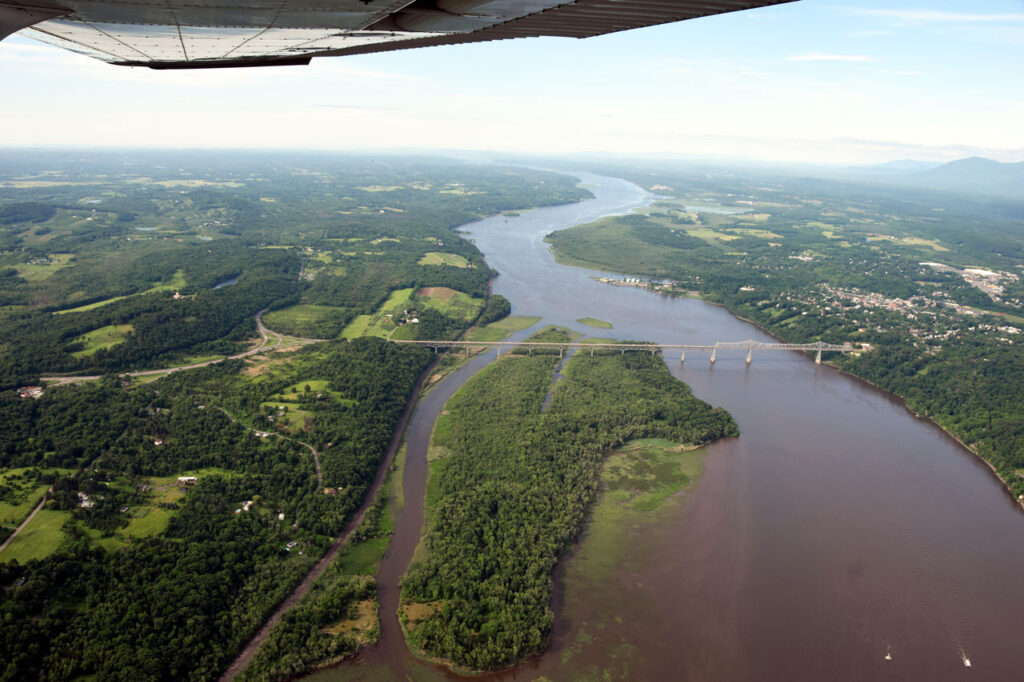 An aerial shot of Rogers Island and the Rip Van Winkle Bridge, with Olana peeking up at left. Image: Jeff Anzevino | Courtesy Scenic Hudson
