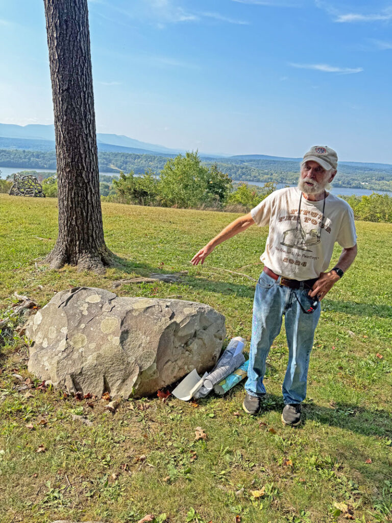 Catskill Geologist Robert Titus points to an especially fine Erratic on Ridge Road, wearing a t-shirt that says "No Glaciers, No Paintings," September 2024. Photo by Annik LaFarge, author of Composing Olana